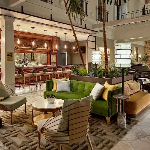 Luxurious lobby bar with green sofa, ornate wooden bar, and piano.