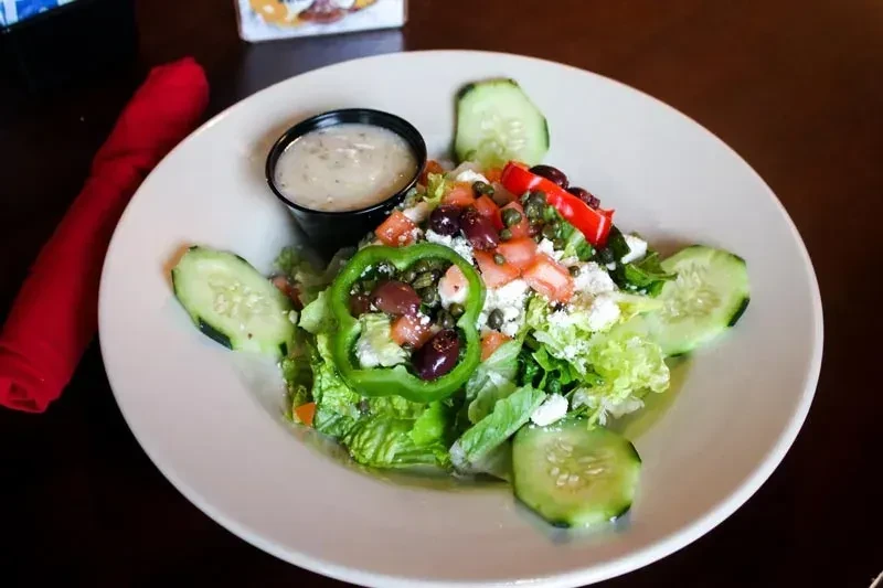 Fresh salad with greens, tomatoes, feta, olives, bell peppers, cucumber, dressing.