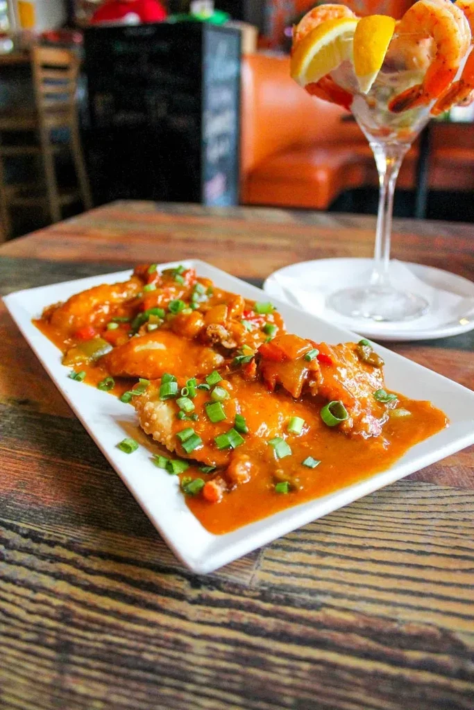 Fried food in reddish sauce, green onions, and shrimp cocktail.
