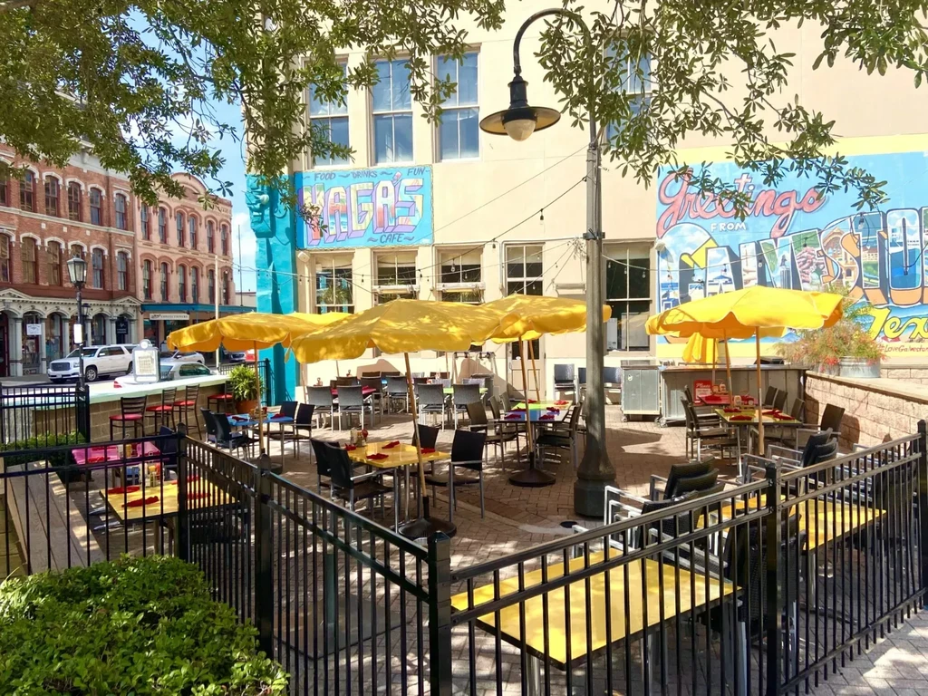 Vagas Cafe outdoor patio with yellow umbrellas and Galveston murals.