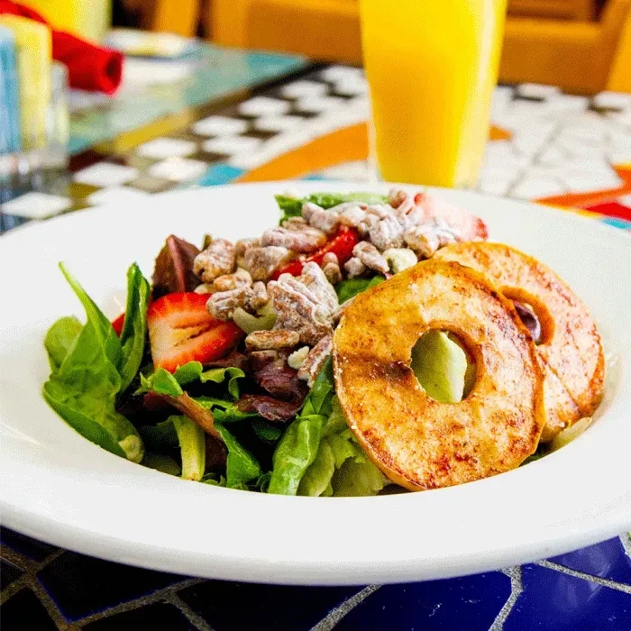 Salad with greens, strawberries, pecans, and roasted apple slices.
