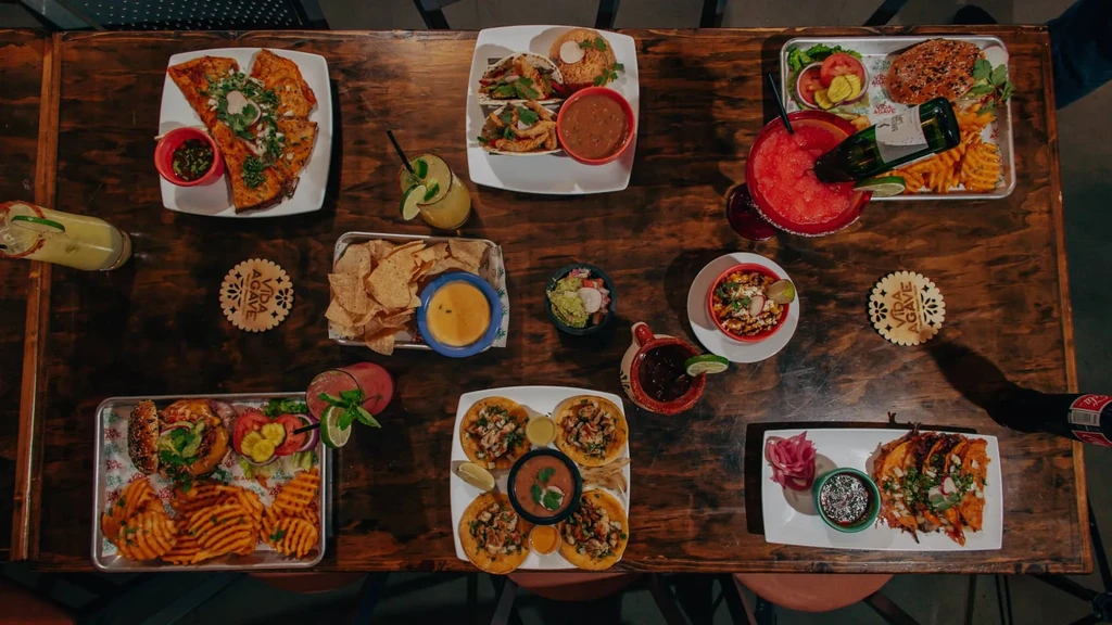 Rustic table with a colorful, abundant spread of Mexican food and drinks.