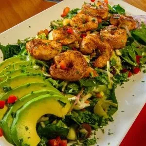 Cooked shrimp and mixed green salad with fanned avocado.