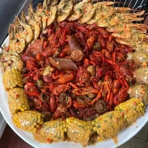 Overflowing seafood boil platter with crawfish, shrimp, corn, and sausage.