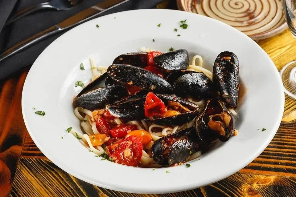 Seafood pasta with mussels, red tomato sauce, and herbs.