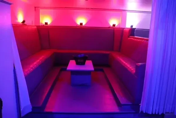 Red and purple U-shaped booth in a dramatically lit lounge.
