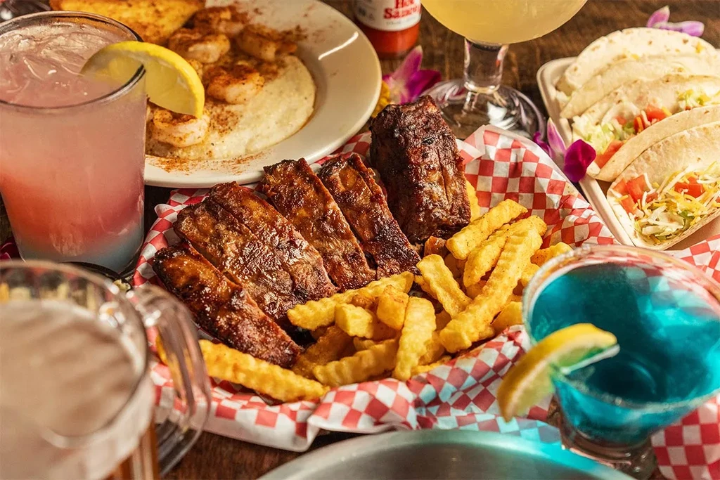 Overhead: Ribs, fries, tacos, shrimp, and colorful cocktails on a table.