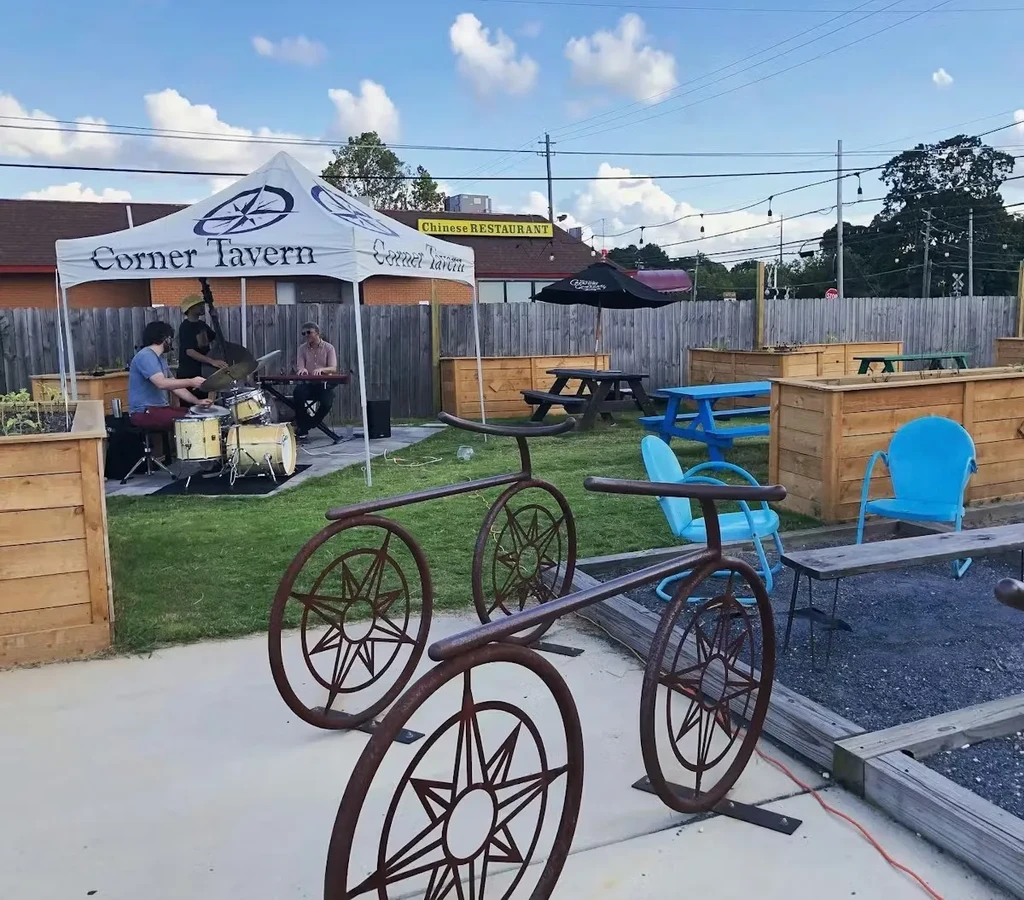 Corner Tavern patio with live band, outdoor seating, and metal sculptures.
