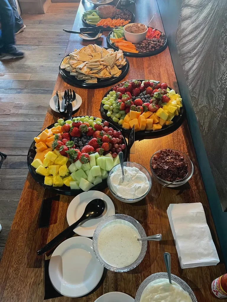 Buffet table laden with fresh fruits, vegetables, and dips.