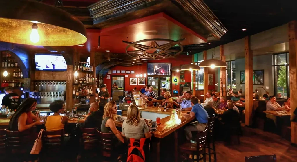 Bustling, modern-industrial restaurant and bar interior with many patrons.