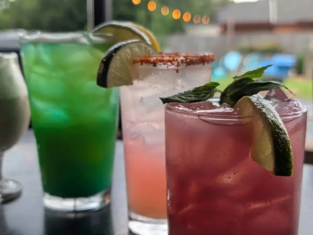 Four vibrant, garnished drinks on a dark table.