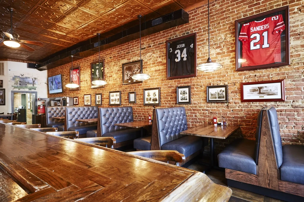 Sports bar interior: wooden bar, leather booths, brick wall, sports jerseys.