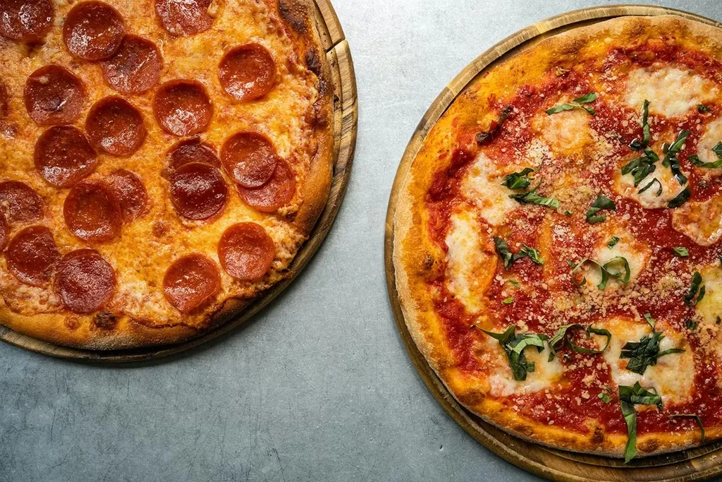 Classic pepperoni and Margherita pizzas on wooden pizza peels.