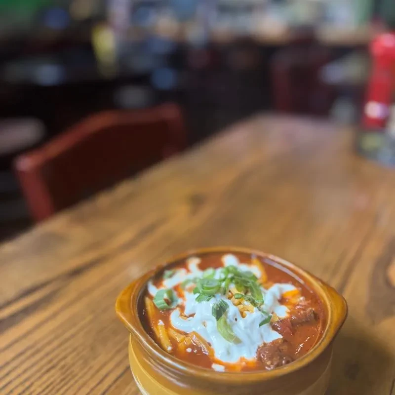 Rustic bowl of chili or stew with sour cream and green onions.
