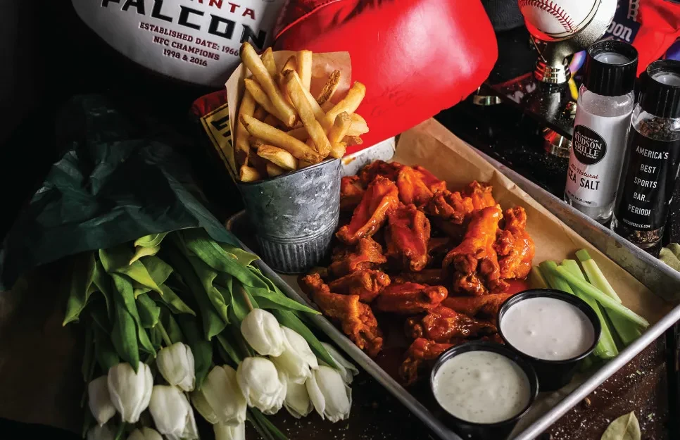 Buffalo wings, fries, and tulips with sports decor in a bar.