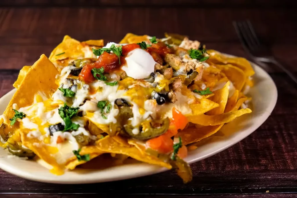 Close-up of loaded nachos with cheese, salsa, sour cream, and jalapeños.