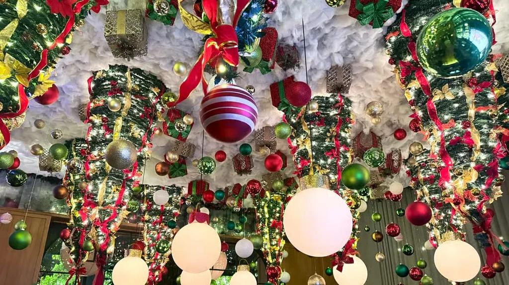 Extensive Christmas decorations hang from a snow-covered ceiling with lights.