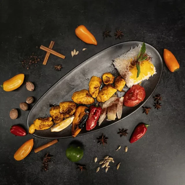 Golden turmeric chicken kebabs, roasted vegetables, and rice on a rustic platter.