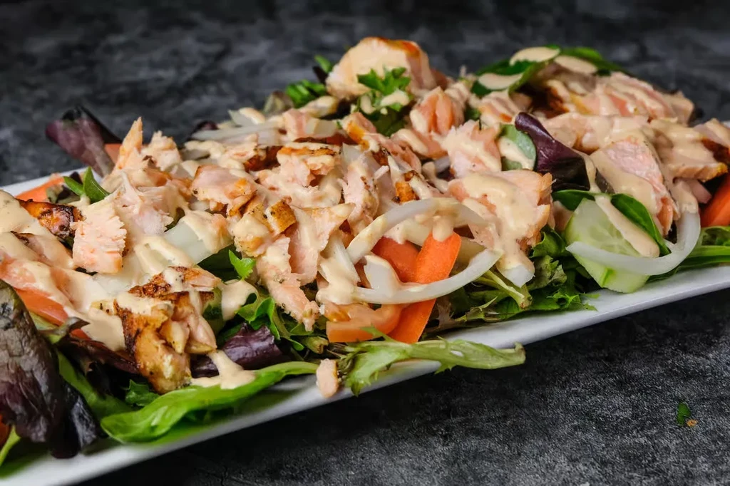 Flaked salmon salad with greens, carrots, cucumber, and creamy dressing.