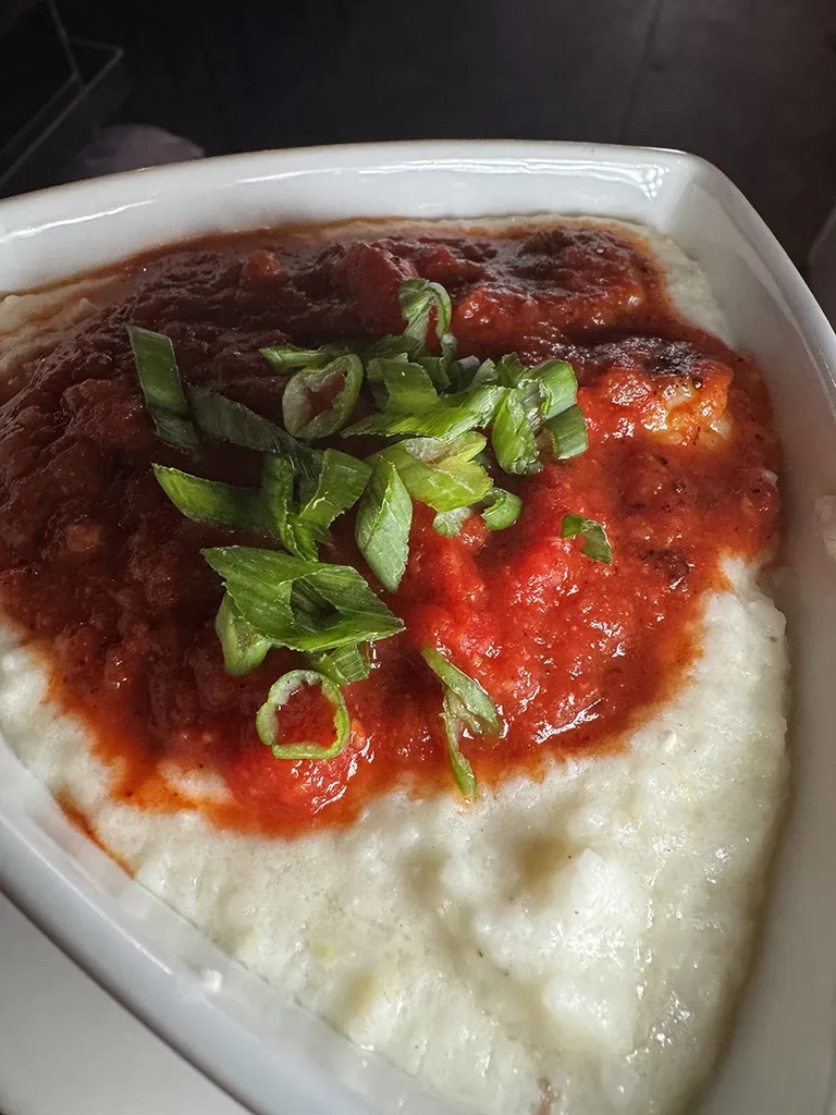 Creamy white grits topped with tomato sauce and fresh scallions.