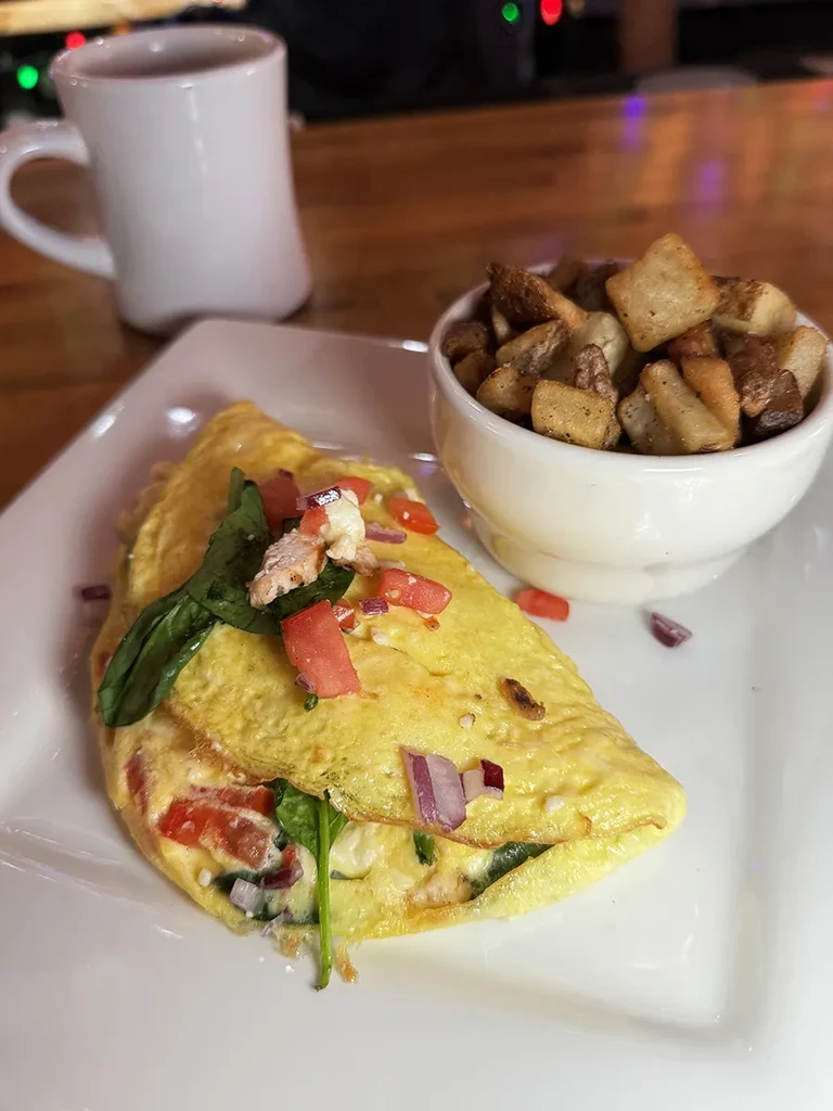 Breakfast plate with a stuffed omelet and crispy cubed potatoes.