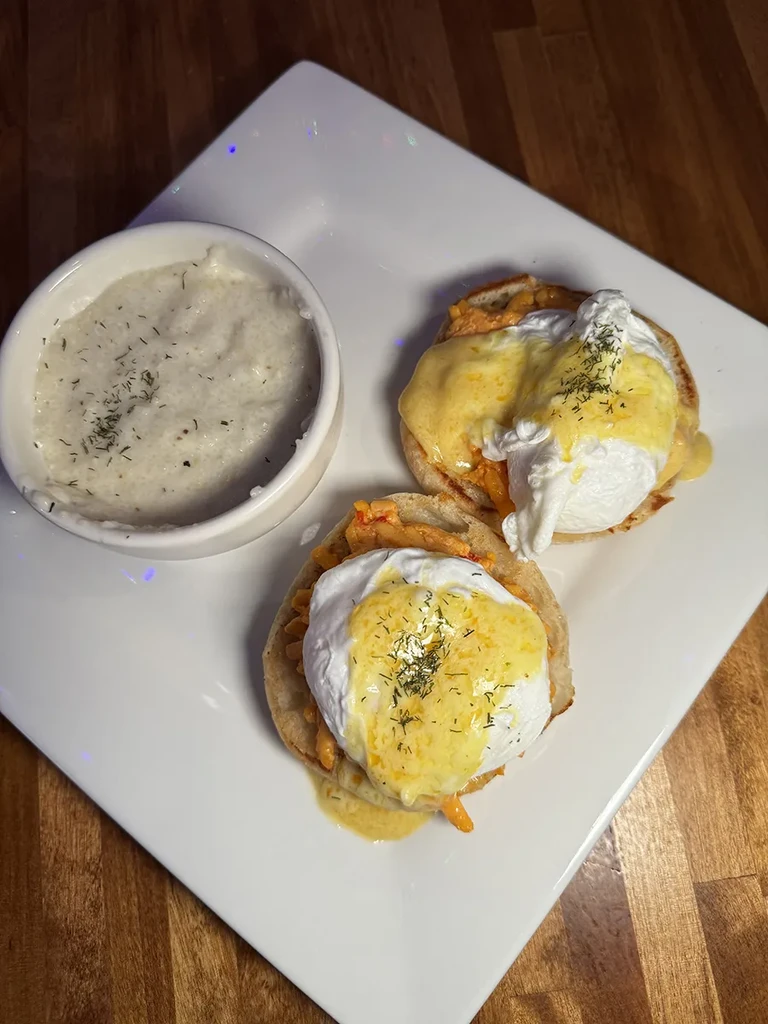 Two servings of eggs Benedict with Hollandaise sauce and creamy side.