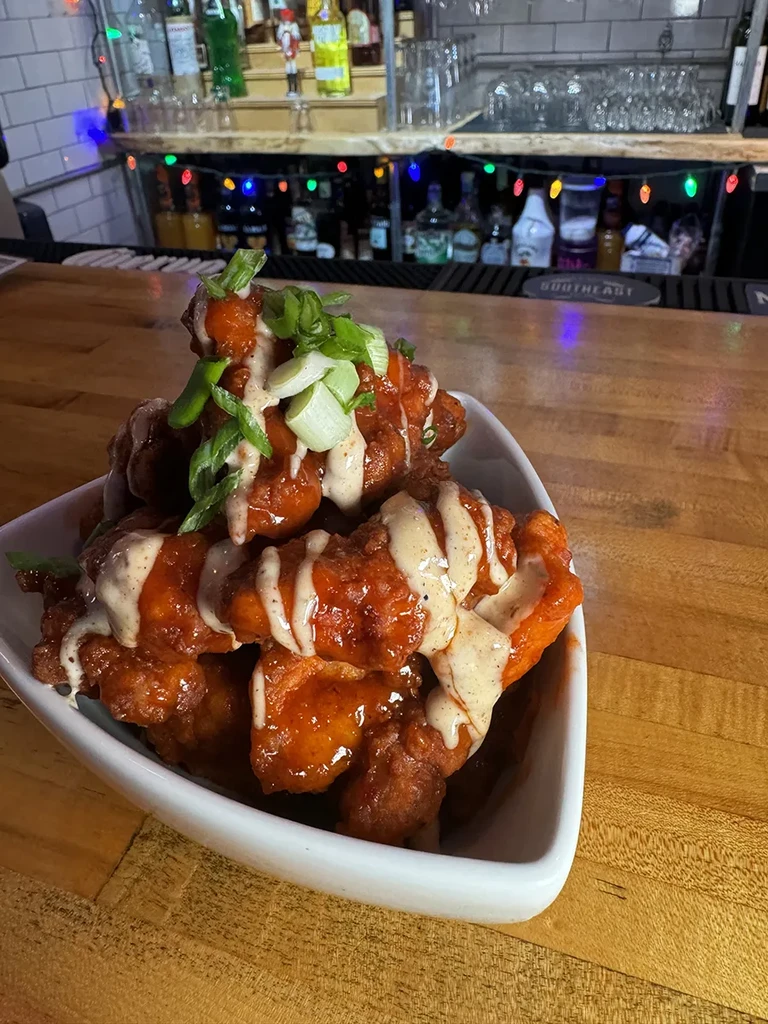 Fried chicken tenders with red and white sauces, green onions.
