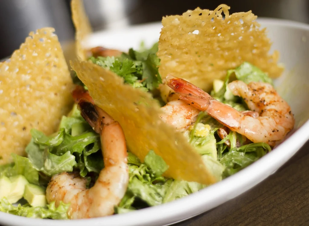 Gourmet shrimp salad with avocado, lettuce, cilantro, and crispy wafers.