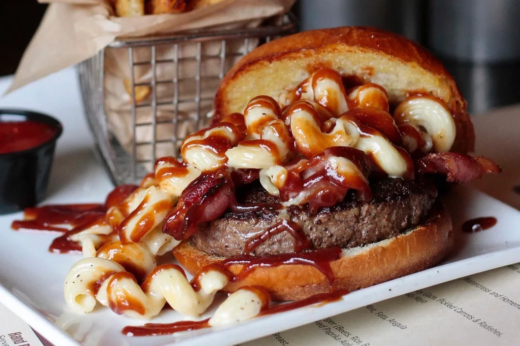 Beef burger with macaroni and cheese, bacon, and fries.