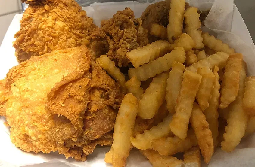 Crispy golden-brown fried chicken and crinkle-cut fries in a container.