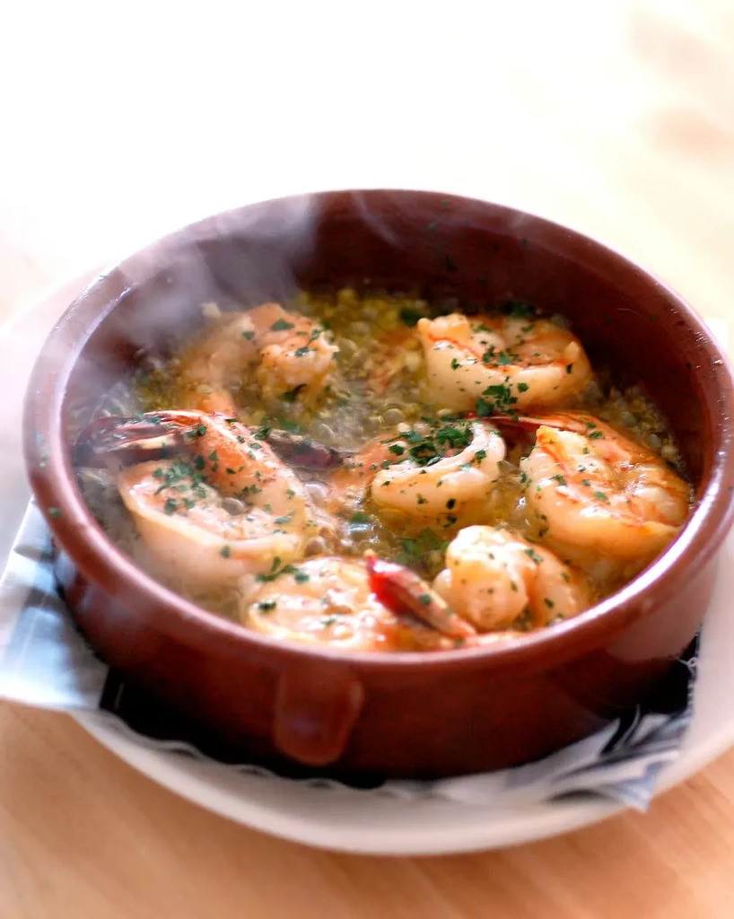 Sizzling garlic shrimp with parsley in a rustic bowl.