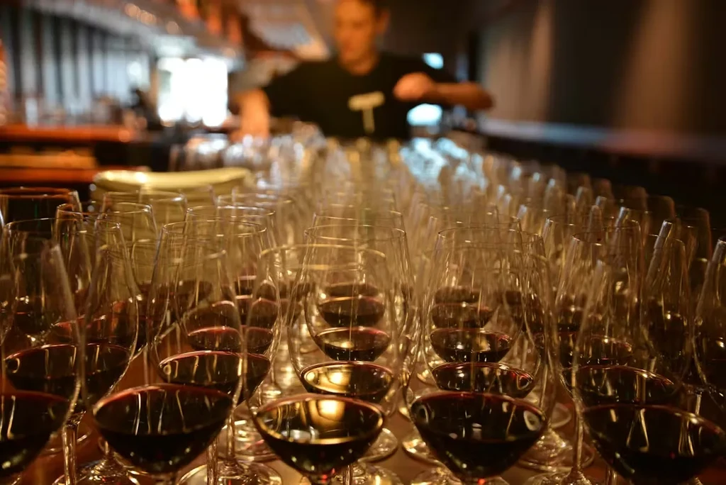 Neat rows of red wine glasses prepared for service in a bar.