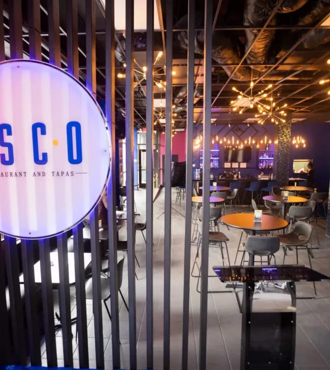 A modern restaurant and tapas interior with a bar and colorful lighting.