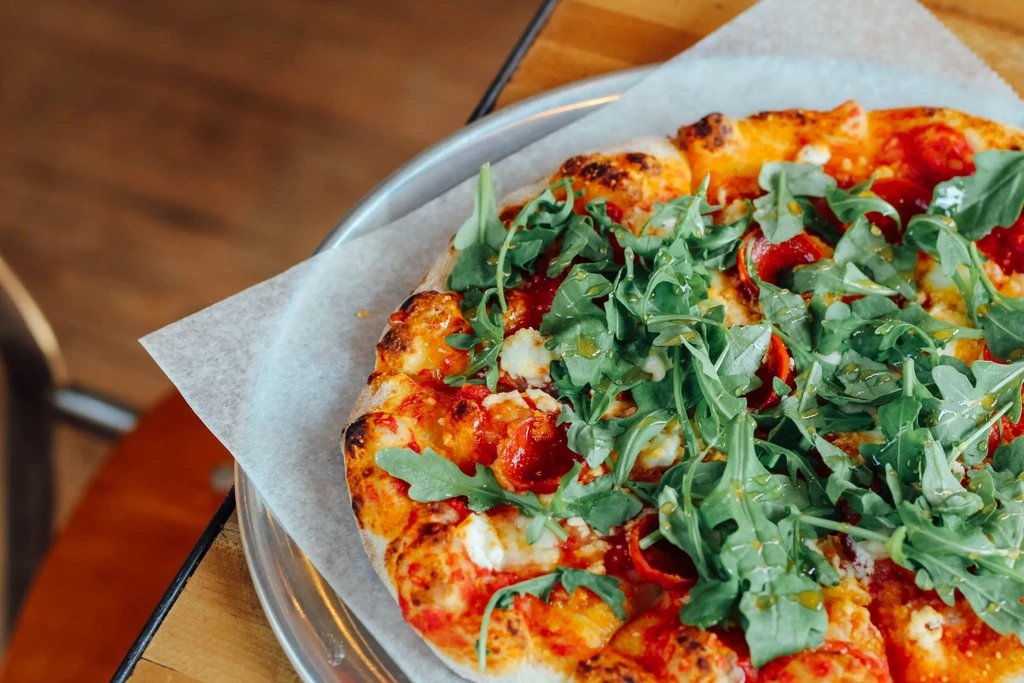 Freshly baked thin-crust pizza with pepperoni, melted cheese, and arugula.