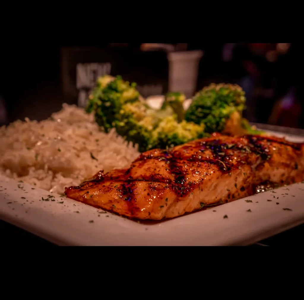 Glazed salmon, white rice, and broccoli on a white plate.