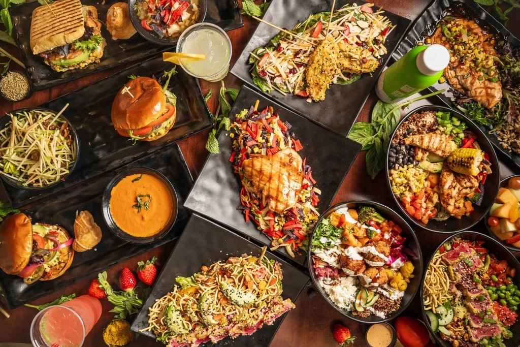 Overhead shot of diverse dishes and drinks, artfully arranged on wood.