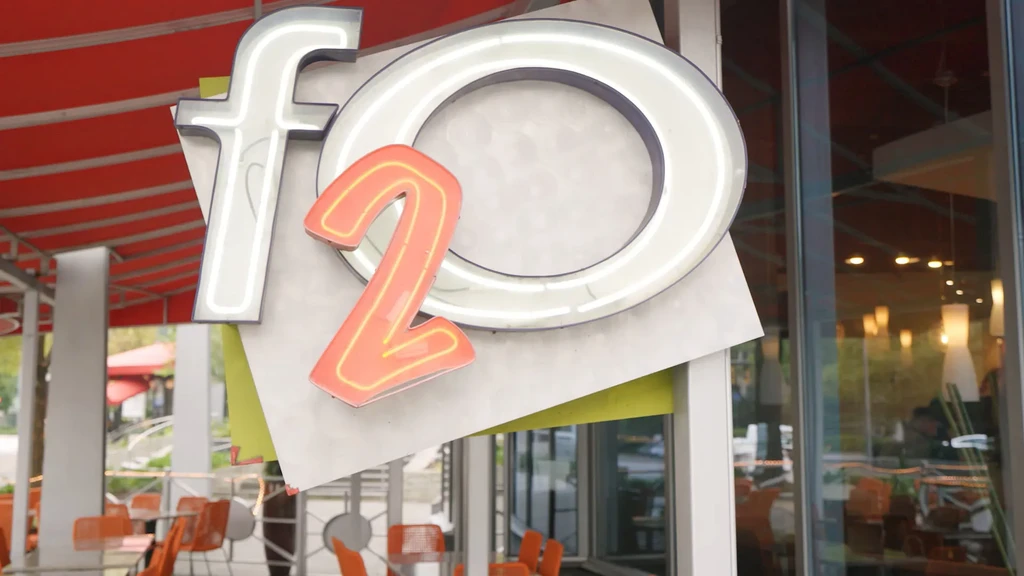 Modern restaurant with retro 'fO2' neon sign and orange patio.