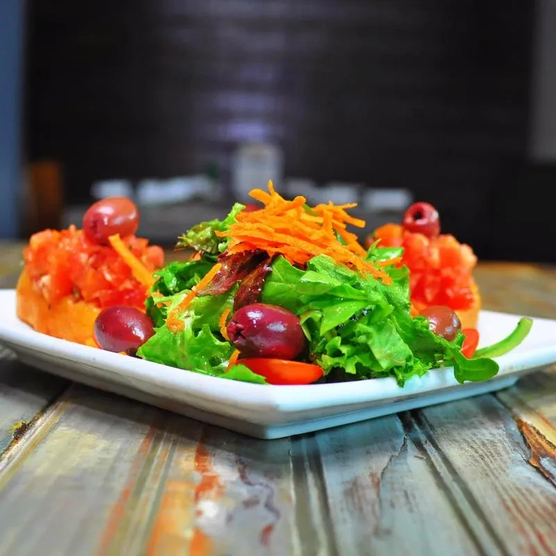 Fresh green salad with carrots and olives, alongside tomato bruschetta.