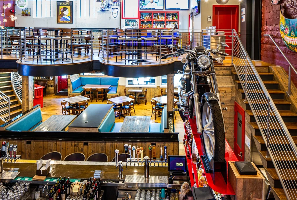 Multi-level restaurant and bar with teal booths and a mounted motorcycle.