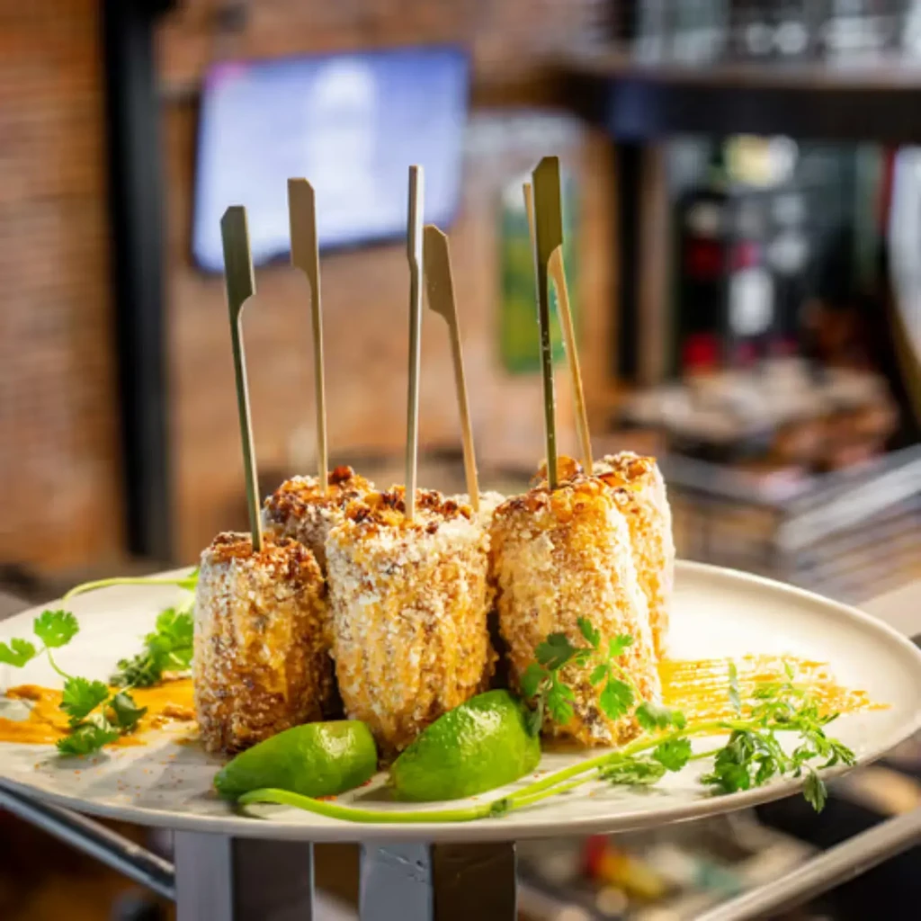 Close-up: Elote-style corn cobs with cheese, spices, lime, and cilantro.