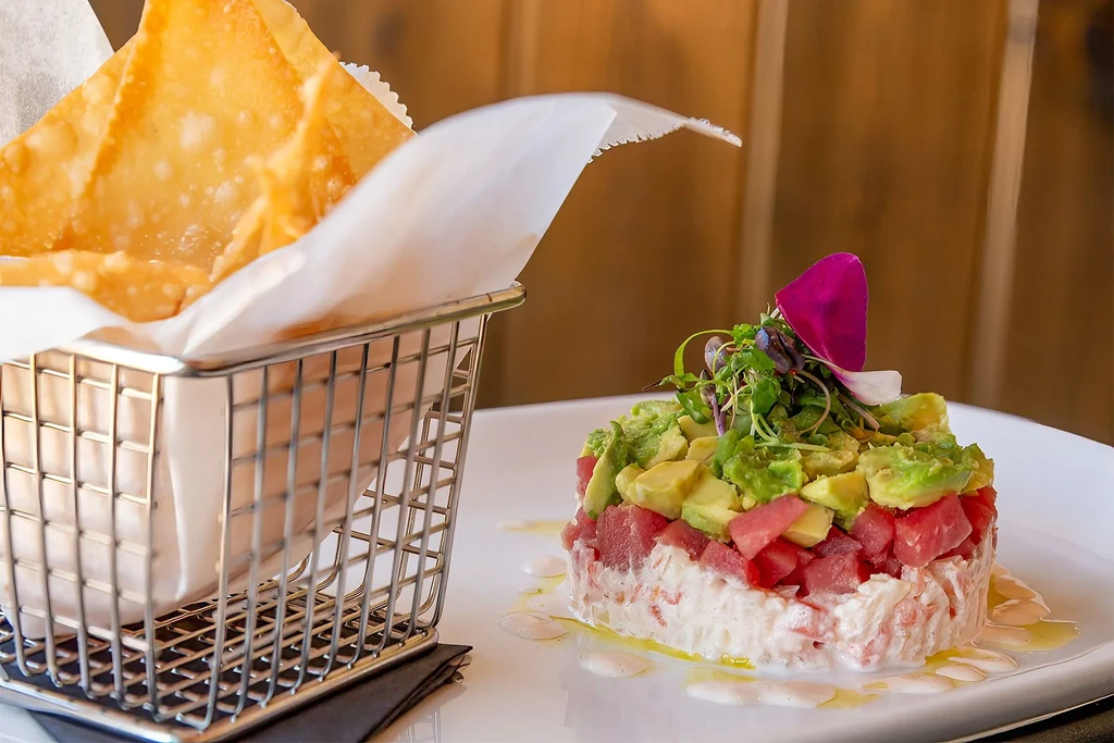 Layered seafood tartare with avocado, microgreens, and crispy chips.