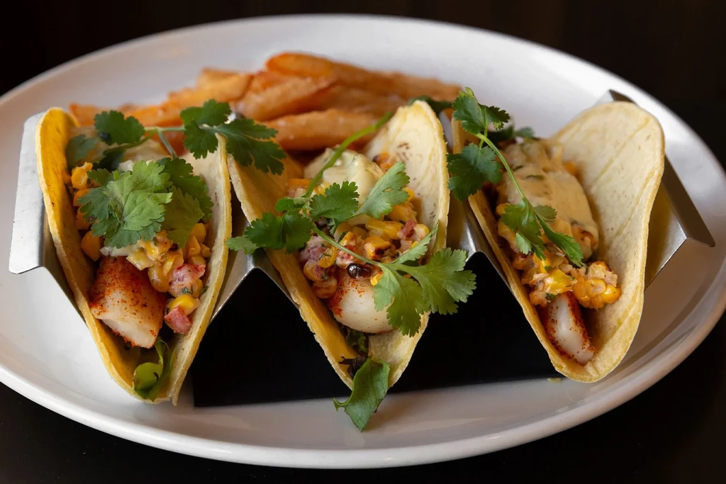 Three fish tacos topped with corn salsa, creamy sauce, and fresh cilantro.