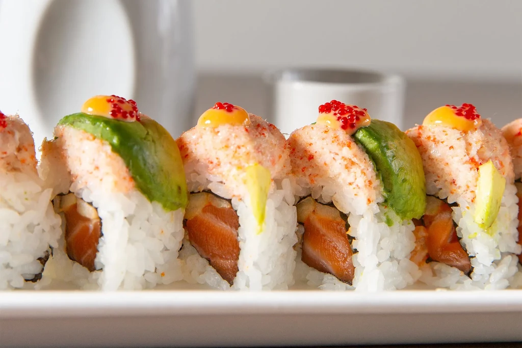 Sushi rolls with salmon, avocado, creamy yellow sauce, and red roe.