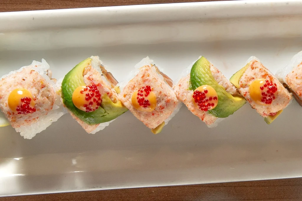 Six sushi rolls topped with pink seafood salad, mayo, and tobiko.