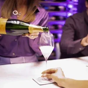 Close-up of sparkling wine poured from a green bottle into a glass.
