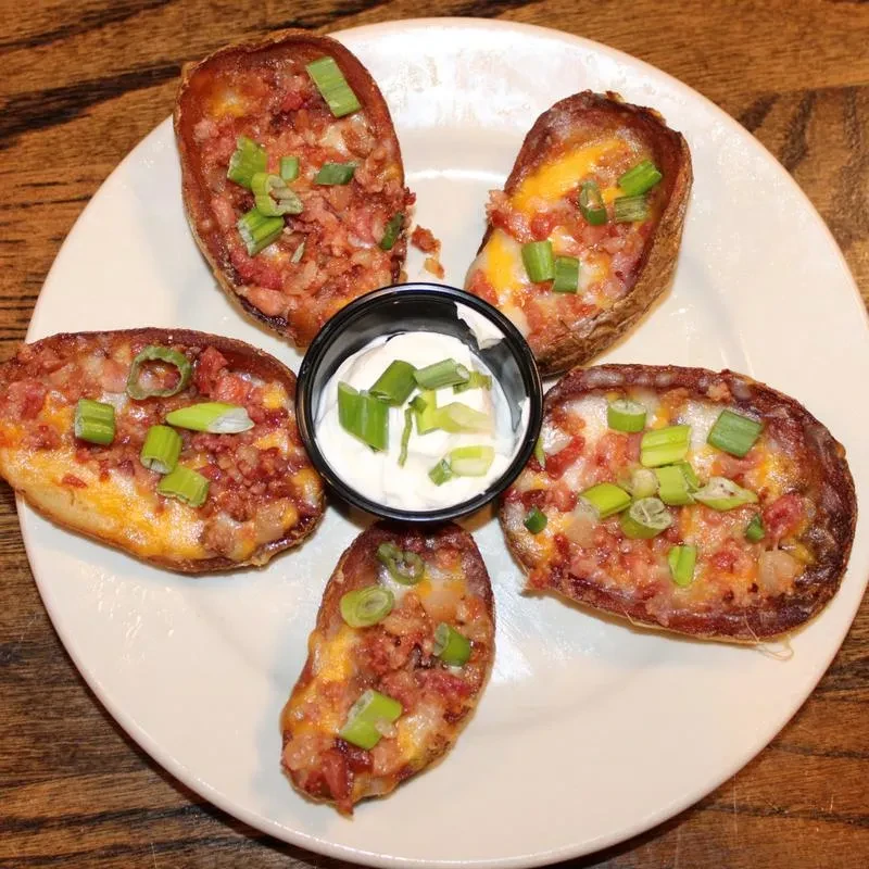 Five loaded potato skins with cheese, bacon, green onions, and sour cream.