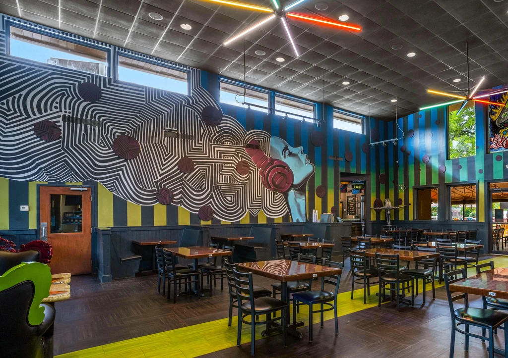 Vibrant modern restaurant with abstract headphone mural and colorful neon lights.