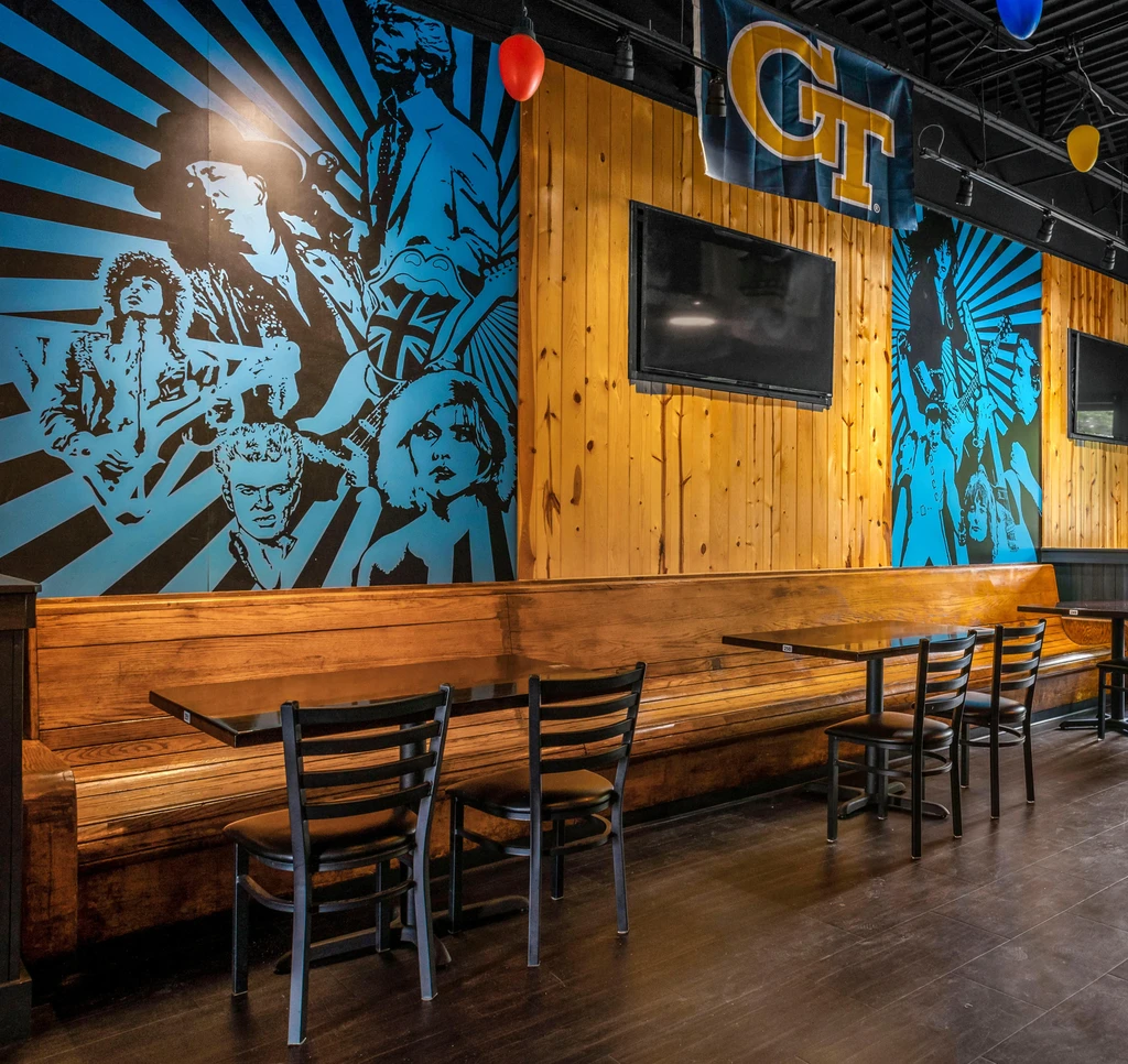 Vibrant restaurant interior with pop-art music icon murals and a GT flag.