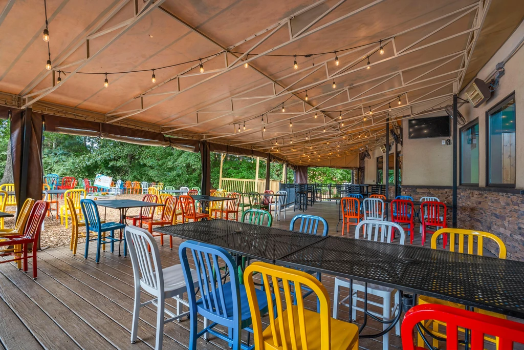 Colorful chairs and metal tables fill a covered outdoor patio.