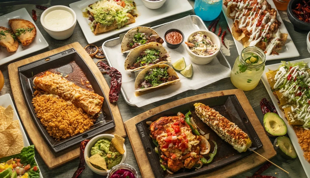Overhead: diverse Mexican and Tex-Mex food and drinks on rustic table.